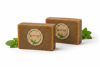 Two bars of Eval Veda soap with mint leaves on a white background